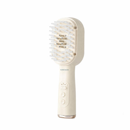 HAIRECOVER cream scalp brush with soft silicone tips and seven metal pins, front three-quarter view on white