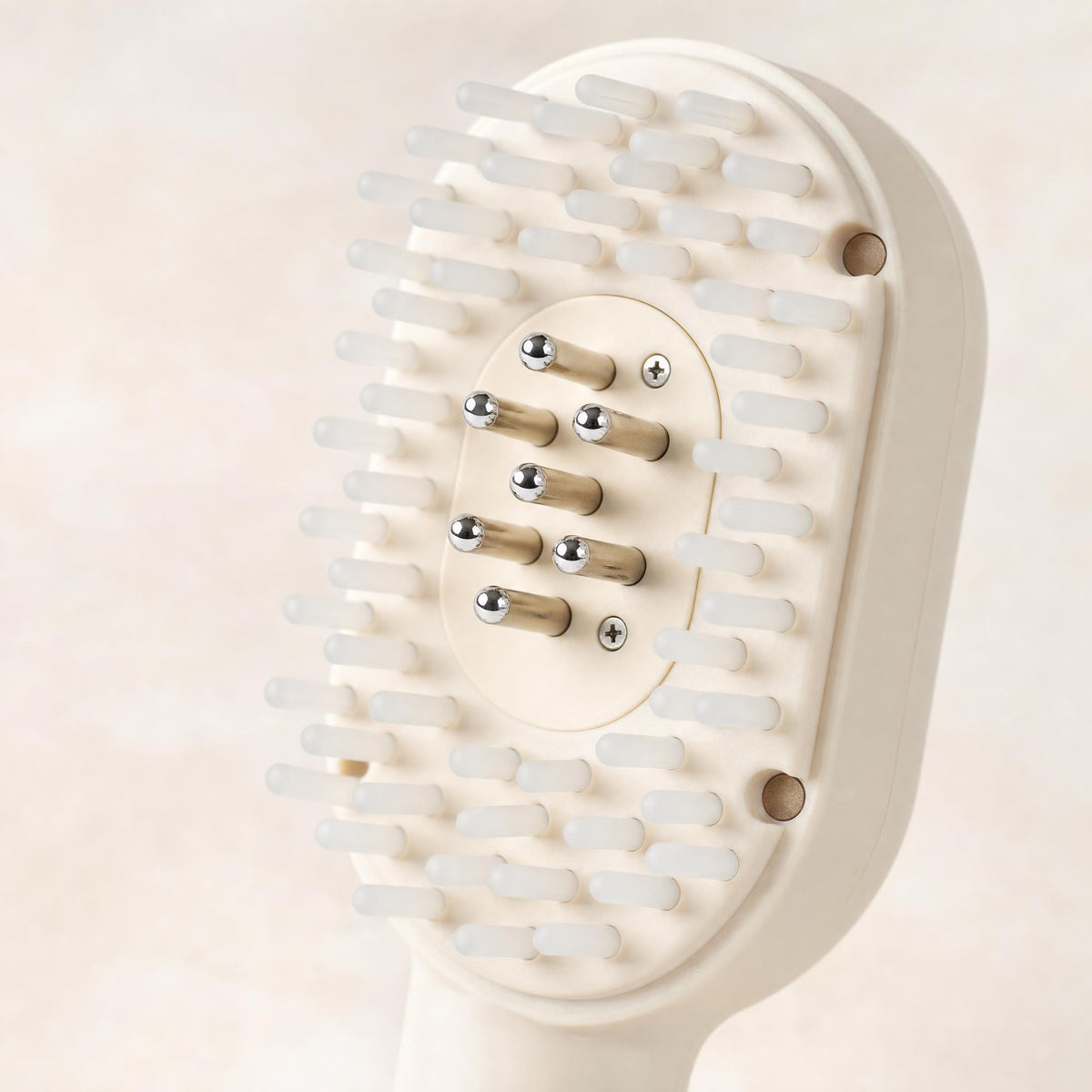 Macro of the HAIRECOVER scalp brush head showing seven metal pins among soft silicone tips