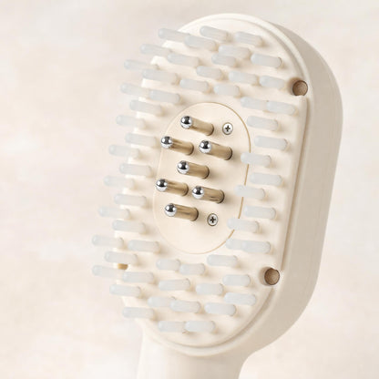 Macro of the HAIRECOVER scalp brush head showing seven metal pins among soft silicone tips