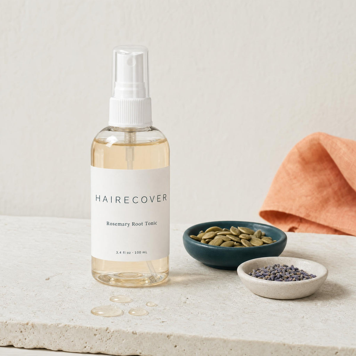 HAIRECOVER Rosemary Root Tonic bottle on stone with small dishes of pumpkin seeds and dried lavender buds