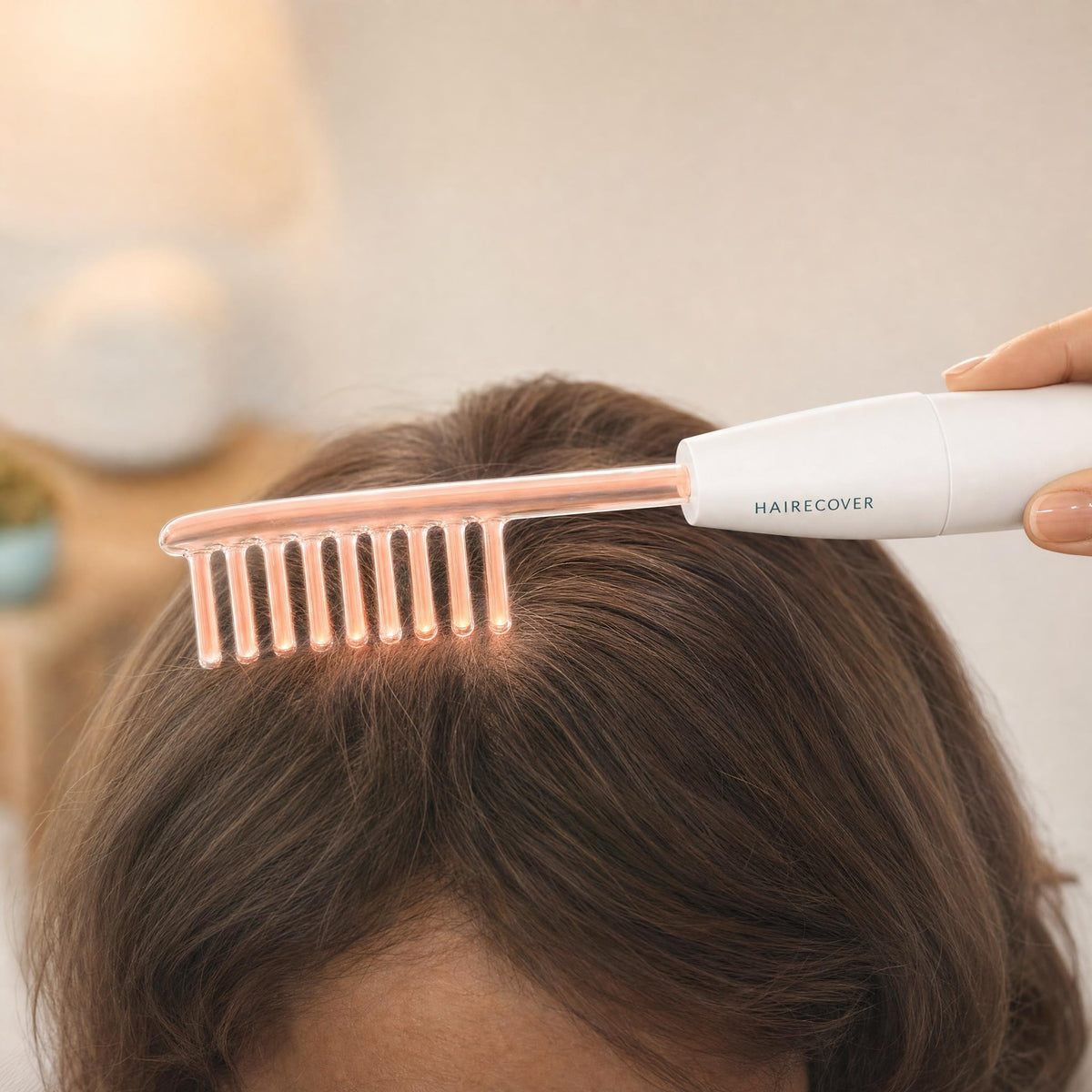 Glowing HAIRECOVER glass comb electrode resting on dry hair on top of the head, attached to the scalp wand
